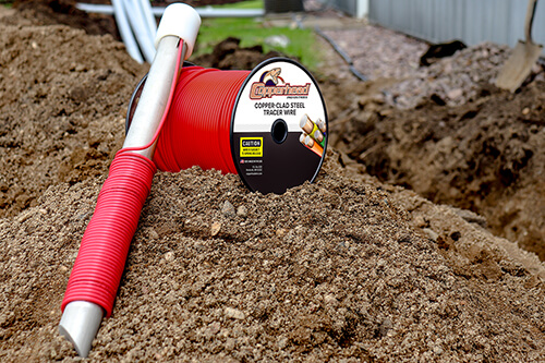 Ground rod laying against red tracer wire in the dirt