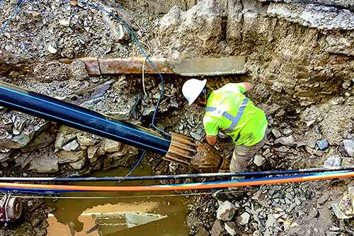 Worker working with blue SoloShot Xtreme tracer wire in the ground