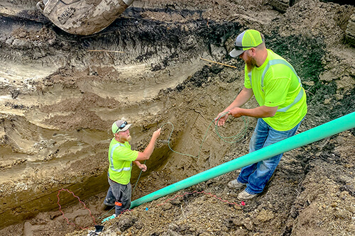 Two men working with green tracer wire