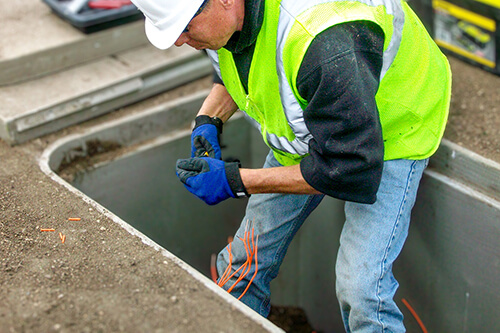 Construction worker adding orange tracer wire