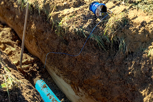 Blue pipe in the ground with blue tracer wire attached