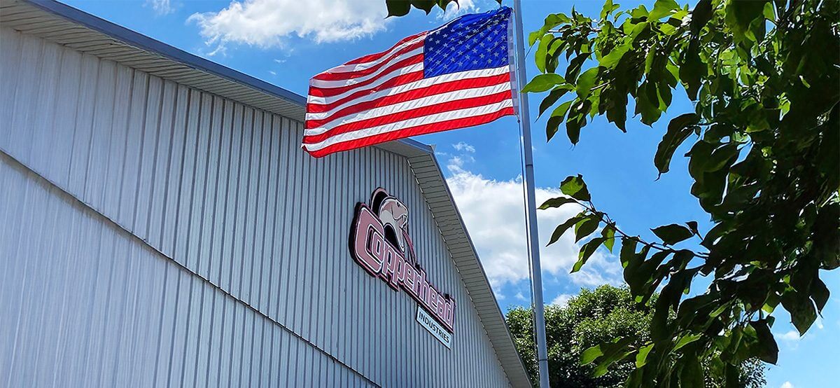 Copperhead logo on side of building with American flag