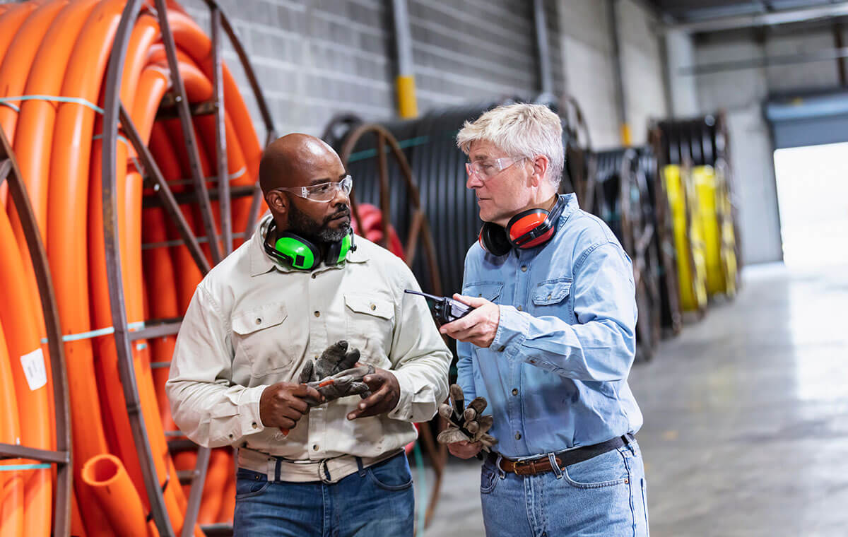 two men with headphones talking around piping