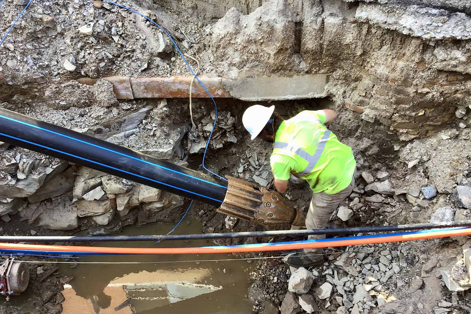 Man in reflective vest adding pipe into the ground