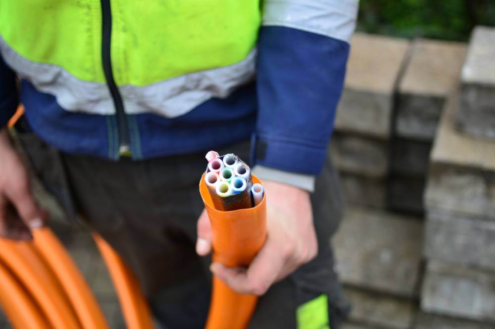 Man holding orange piping for Telecommunication